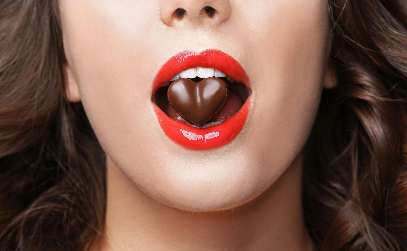 girl taking heart shape chocolate inred lips